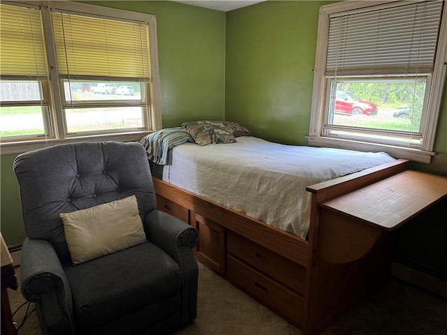 carpeted bedroom with multiple windows and a baseboard heating unit