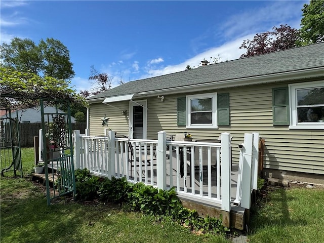 back of house with a wooden deck, fence, and a shingled roof