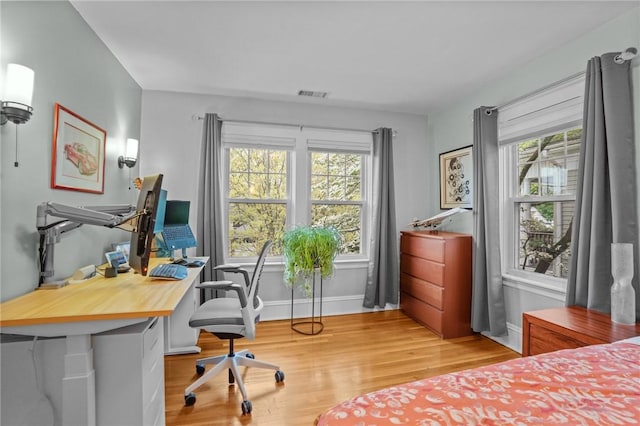 bedroom featuring multiple windows, light wood-style floors, baseboards, and an office area