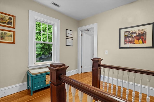 hallway featuring an upstairs landing, baseboards, and light wood-type flooring