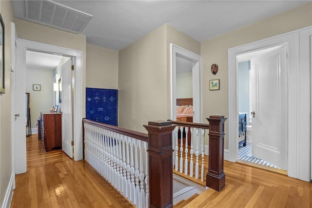 hallway featuring an upstairs landing, light wood-style flooring, and baseboards