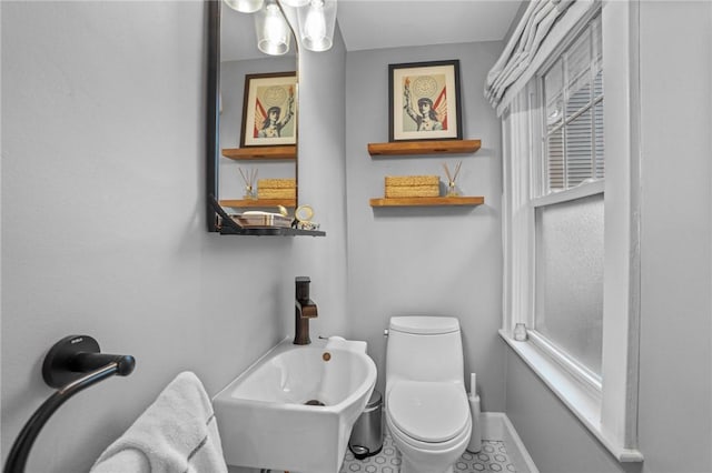 bathroom with toilet, baseboards, and a sink