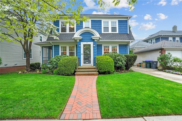 view of front of house featuring a front lawn and roof with shingles