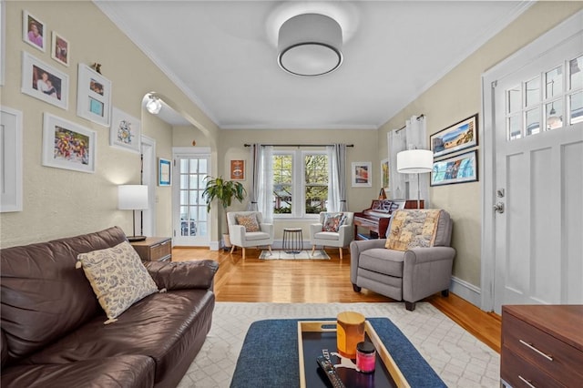living room featuring wood finished floors, ornamental molding, and baseboards
