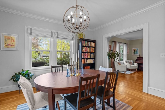 dining area with a chandelier, light wood-style flooring, crown molding, and baseboards