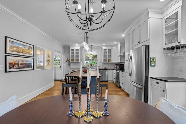 dining room with light wood-style flooring, a chandelier, recessed lighting, ornamental molding, and baseboards