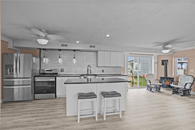 kitchen with stainless steel appliances, a ceiling fan, a wood stove, a sink, and recessed lighting