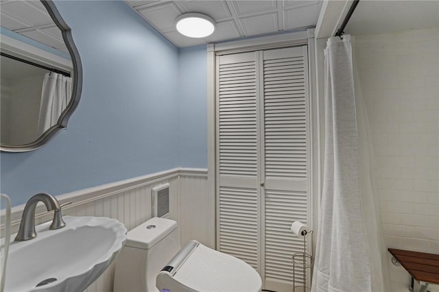 bathroom featuring a sink, a wainscoted wall, and toilet