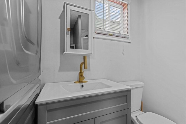 bathroom with vanity, toilet, and washer / dryer