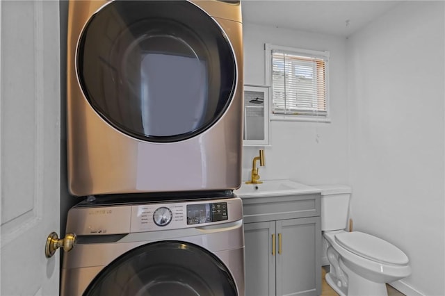 washroom with stacked washer and clothes dryer and baseboards