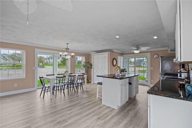 kitchen with ornamental molding, white cabinetry, baseboards, light wood-style flooring, and plenty of natural light