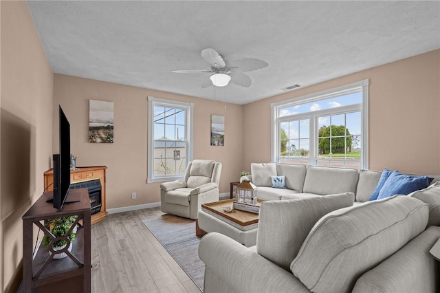 living area with wood finished floors, a ceiling fan, baseboards, and a fireplace