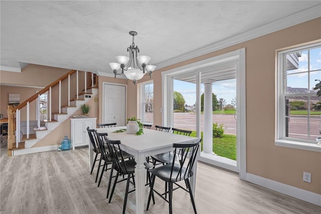 dining space with stairway, light wood-type flooring, baseboards, a chandelier, and ornamental molding