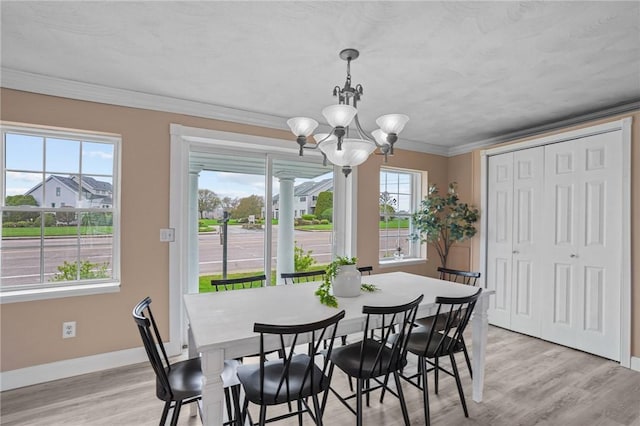 dining room with a chandelier, light wood finished floors, baseboards, and crown molding