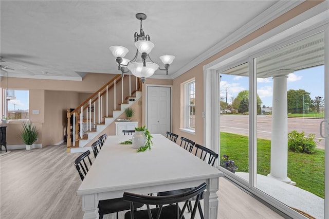 dining room featuring ornamental molding, stairway, a chandelier, baseboards, and light wood-style flooring