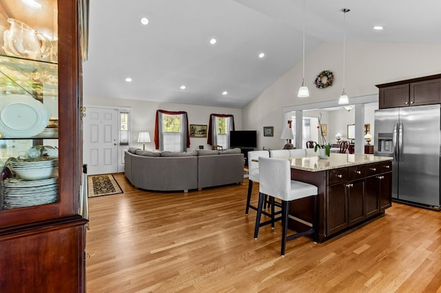 1740 Bulgarmarsh Rd, Tiverton, RI 02878 - kitchen with stainless steel fridge, a kitchen breakfast bar, dark brown cabinets, light wood-type flooring, and high vaulted ceiling