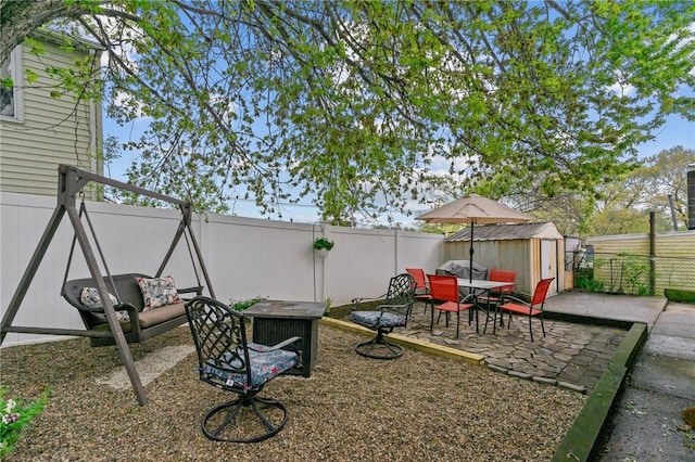 fenced backyard featuring a shed, an outdoor structure, a patio, and outdoor dining space