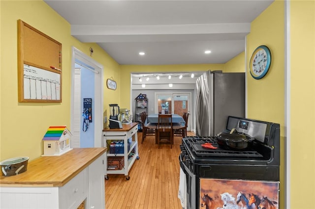 kitchen featuring range with gas cooktop, freestanding refrigerator, butcher block countertops, light wood finished floors, and white cabinets