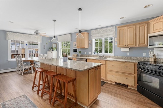 kitchen with light brown cabinets, stainless steel microwave, black electric range oven, and a sink