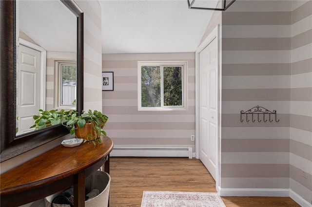 corridor featuring a baseboard heating unit and wood finished floors