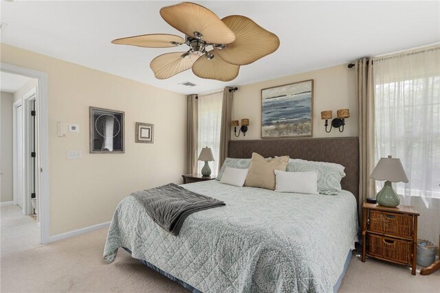 bedroom featuring light colored carpet, multiple windows, ceiling fan, and baseboards