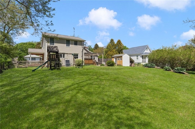 rear view of property featuring a shed, a playground, and an outbuilding