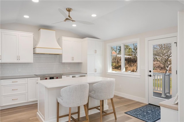 9 Stedman Rd, South Kingstown, RI 02879 - kitchen with custom range hood, vaulted ceiling, light wood-style floors, white cabinets, and recessed lighting