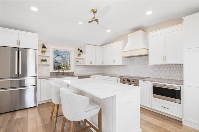 9 Stedman Rd, South Kingstown, RI 02879 - kitchen with stainless steel appliances, custom range hood, open shelves, light wood-style flooring, and backsplash
