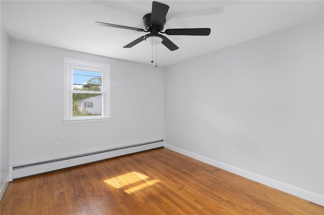 empty room featuring a baseboard heating unit, wood finished floors, baseboards, and ceiling fan