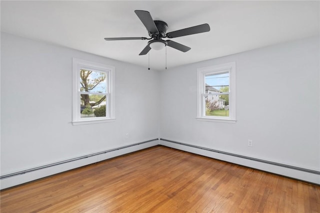 empty room with healthy amount of natural light, light wood-style flooring, baseboard heating, and a ceiling fan