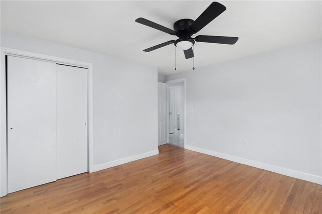 unfurnished bedroom with baseboards, light wood-type flooring, a closet, and ceiling fan