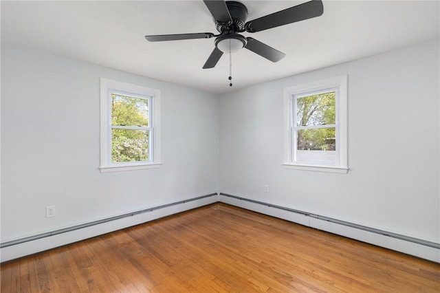 spare room with healthy amount of natural light, wood finished floors, and baseboard heating