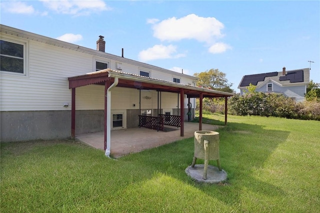 rear view of house featuring a patio area, a lawn, and a chimney