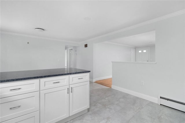 kitchen featuring baseboard heating, white cabinetry, ornamental molding, baseboards, and dark stone countertops