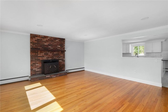unfurnished living room featuring baseboard heating, a baseboard radiator, light wood finished floors, crown molding, and a fireplace