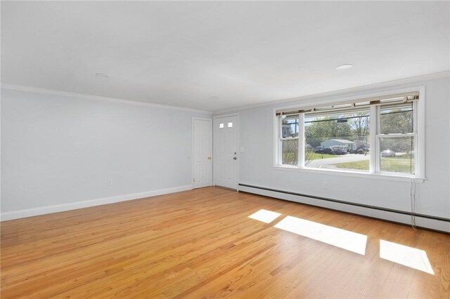 unfurnished living room with baseboard heating, ornamental molding, light wood-style floors, and baseboards