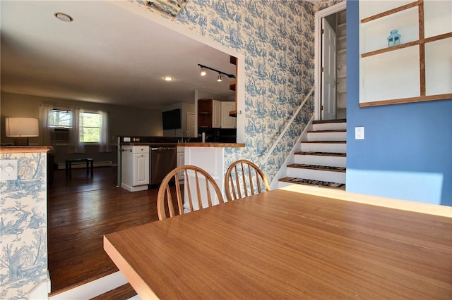 dining room featuring a baseboard heating unit, wallpapered walls, dark wood finished floors, stairs, and baseboards