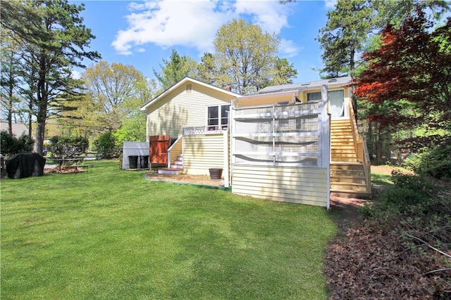 back of property featuring stairway, a lawn, and a wooden deck