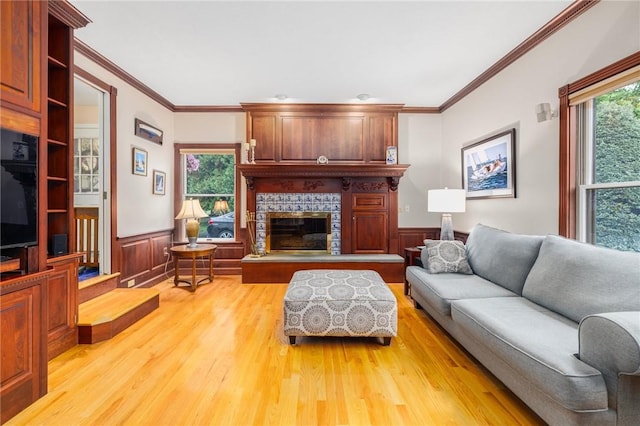 831 N Quidnessett Rd, North Kingstown, RI 02852 - living room featuring wainscoting, healthy amount of natural light, ornamental molding, light wood-type flooring, and a fireplace