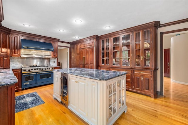 831 N Quidnessett Rd, North Kingstown, RI 02852 - kitchen with custom range hood, range with two ovens, light wood-type flooring, glass insert cabinets, and decorative backsplash