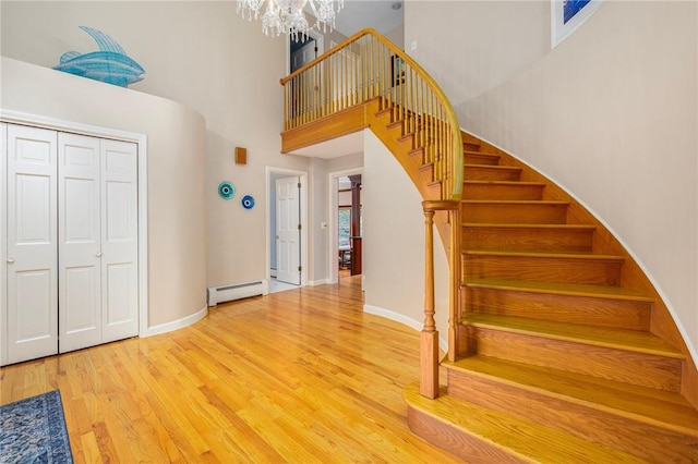 831 N Quidnessett Rd, North Kingstown, RI 02852 - stairway featuring a chandelier, a high ceiling, wood finished floors, a baseboard radiator, and baseboards