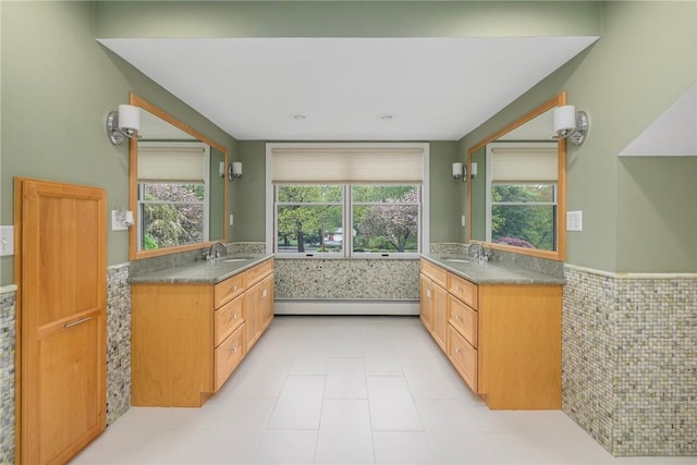 831 N Quidnessett Rd, North Kingstown, RI 02852 - bathroom with baseboard heating, two vanities, a wainscoted wall, tile patterned flooring, and tile walls