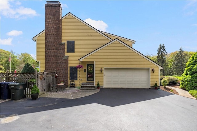 831 N Quidnessett Rd, North Kingstown, RI 02852 - view of front of property with a chimney, asphalt driveway, a garage, and fence