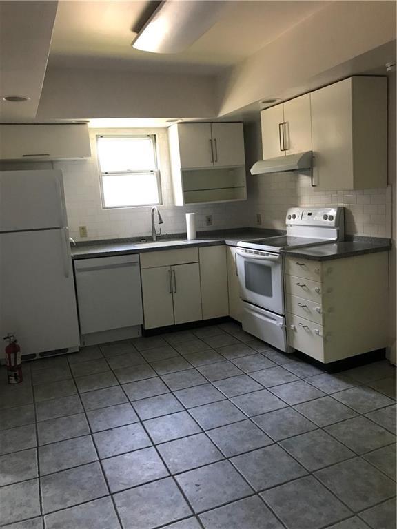 16 Gough Ave, West Warwick, RI 02893 - kitchen with white appliances, a sink, backsplash, under cabinet range hood, and dark countertops