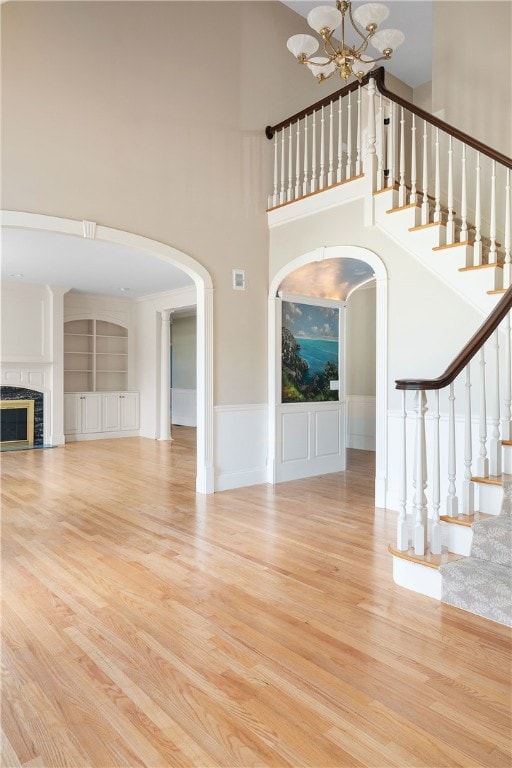 38 Miss Fry Dr, East Greenwich, RI 02818 - unfurnished living room with wood finished floors, a high ceiling, a chandelier, arched walkways, and a fireplace