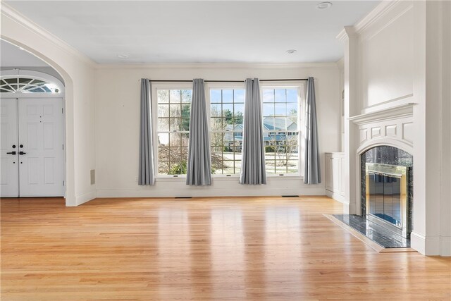 38 Miss Fry Dr, East Greenwich, RI 02818 - unfurnished living room with light wood-style floors, crown molding, arched walkways, healthy amount of natural light, and a premium fireplace