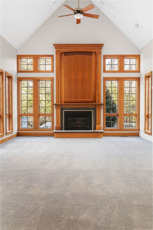 38 Miss Fry Dr, East Greenwich, RI 02818 - unfurnished living room featuring high vaulted ceiling, a ceiling fan, a glass covered fireplace, and carpet