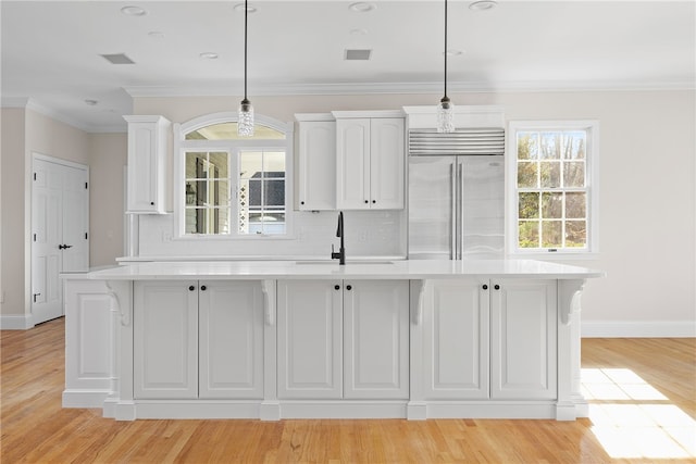 38 Miss Fry Dr, East Greenwich, RI 02818 - kitchen featuring built in refrigerator, a sink, white cabinets, light countertops, and ornamental molding