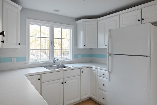 38 Miss Fry Dr, East Greenwich, RI 02818 - kitchen with freestanding refrigerator, a sink, backsplash, and white cabinetry