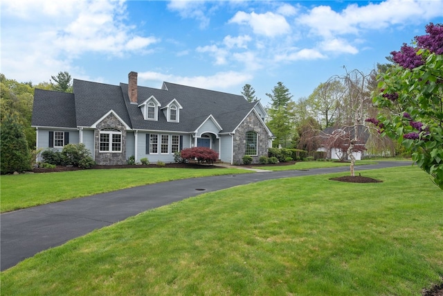38 Miss Fry Dr, East Greenwich, RI 02818 - view of front of house with stone siding, a front yard, a chimney, and asphalt driveway